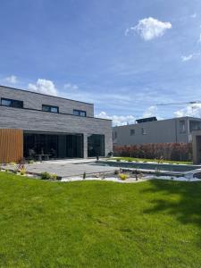a modern house with a grassy yard in front of a building at Executive Villa with pool in Londerzeel +19 photos