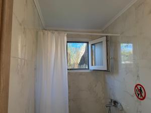 a bathroom with a shower curtain and a window at Vasiliki Little House in Kanoni