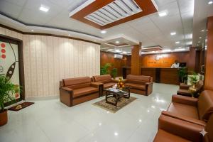 a waiting room with brown leather chairs and a table at Hotel Sweet Place in Dhaka