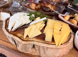 a plate of cheese on a wooden cutting board at Pouso das Flores - Próximo a Maria Fumaça in Tiradentes