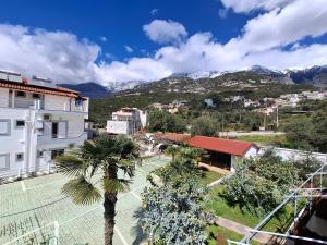 a city with buildings and palm trees and mountains at Yard Paradise Rooms in Dhërmi