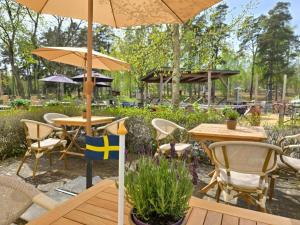 a patio with tables and chairs and an umbrella at Norrqvarn Hotel & Resort by Vänerport in Lyrestad