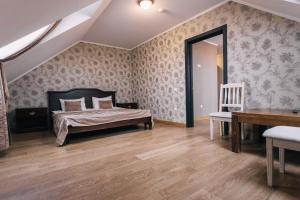 a bedroom with a bed and a table and a chair at Biдень in Lviv