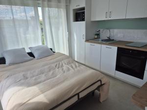 a bedroom with a bed and a kitchen with white cabinets at Le cocoon idyllique in Faverolles-sur-Cher