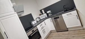 a kitchen with white cabinets and a black counter top at Ostsee No8 Eckernförde in Eckernförde