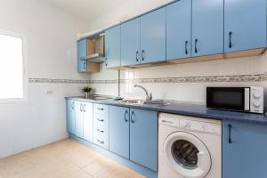a kitchen with blue cabinets and a washing machine at Apartamento Los Angeles Cerca Estación Tren Aeropuerto in Málaga