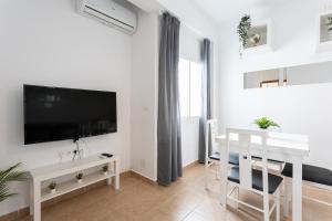 a white living room with a tv and a table at Apartamento Los Angeles Cerca Estación Tren Aeropuerto in Málaga
