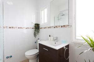 a white bathroom with a toilet and a sink at Apartamento Los Angeles Cerca Estación Tren Aeropuerto in Málaga +10 photos