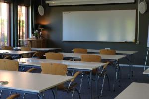an empty classroom with tables and chairs and a whiteboard at Norrqvarn Hotel & Resort by Vänerport in Lyrestad