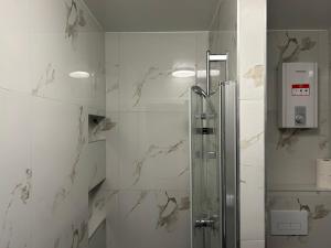 a shower stall in a bathroom with white tiles at Noble Rooms Saarbrücken in Saarbrücken