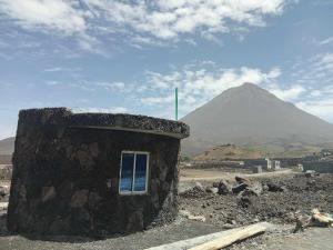 a small stone building with a mountain in the background at Funco Vulcao in Cova Figueira