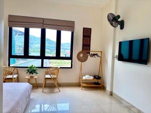 a bedroom with a bed and two chairs and a tv at Pá Homestay - Thành phố Cao Bằng in Cao Bằng