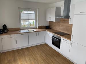 a kitchen with white cabinets and a sink and a window at Ferienwohnung unterm Äpflet in Furth im Wald