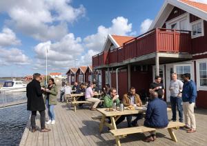 a group of people standing on a dock with a building at Havets Magasin in Väjern