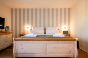 a bedroom with a white bed with a striped wall at Restaurant & Pension Skipper Zingst in Zingst +36 photos