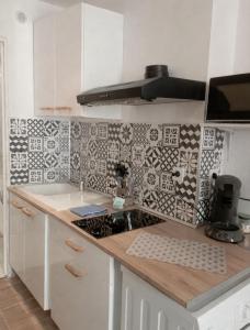 a kitchen with white cabinets and black and white tiles at Le Cocon du Ventoux Studio cosy à Carpentras in Carpentras