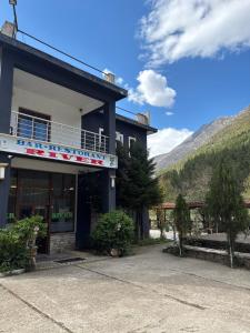 a building with a mountain in the background at Bar-Restaurant-Hotel River in Këlcyrë Fshat