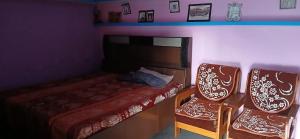 a small bedroom with a bed and two chairs at Sandeep Homes in Tehri-Garhwāl