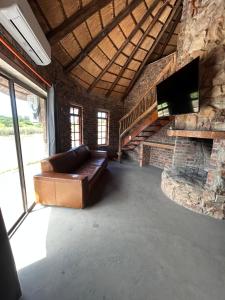 a living room with a leather couch and a stone fireplace at DaisyRiver Cottage in Port Alfred