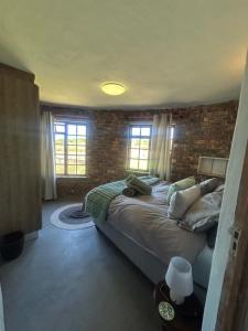 a bedroom with a large bed in a brick wall at DaisyRiver Cottage in Port Alfred