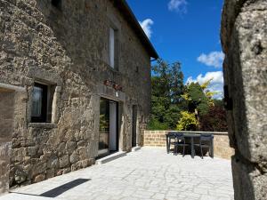a stone building with a table and chairs on a patio at Gîte de Charme in Saint-Avit-de-Tardes