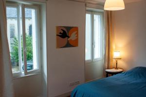 a bedroom with a bed and two windows at Le Petit Marigny in Marigny-lʼÉglise