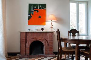 a living room with a brick fireplace and a table at Le Petit Marigny in Marigny-lʼÉglise