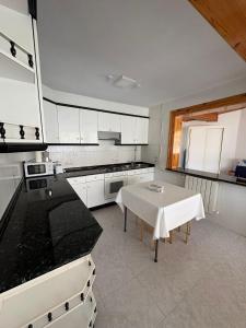 a kitchen with a white table and a white counter top at Alojamiento caral in Laxe