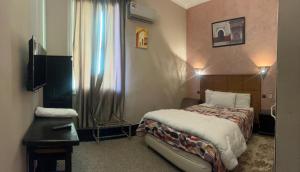a bedroom with a bed and a table and a window at Amor Hotel in Fez