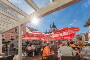 a group of people sitting at a restaurant under umbrellas at Hotel Himmelreich in Mariazell