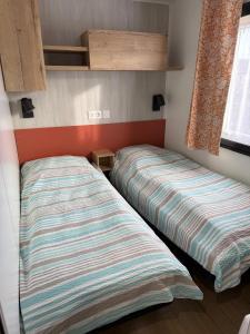 two beds in a small room with a bedskirtsermottermott at Finca Leberto in Renesse