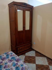 a bedroom with a wooden cabinet and a tiled floor at Location près de la plage in Tichi
