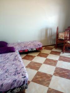 a room with two beds and a checkered floor at Location près de la plage in Tichi