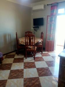 a dining room with a table and chairs and a checkerboard floor at Location près de la plage in Tichi