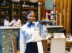 a waitress holding a plate of food in a restaurant at Lifestyle Boutique Hotel in Lilongwe +44 photos
