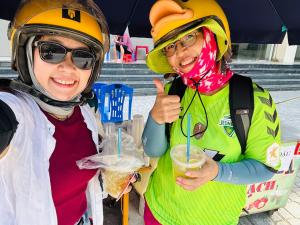 two women wearing helmets and giving a thumbs up at La Maison de My Tho in Mỹ Tho