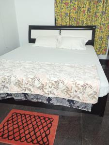 a bedroom with a bed with a white bedspread and a rug at Misty Hills in Yercaud