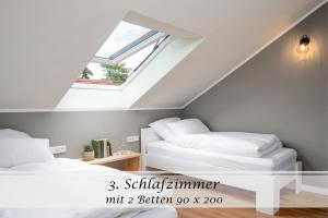 two beds in a attic room with a window at Ferienwohnung Freia - Gulfhof nahe Greetsiel mit Sauna, Garten & 3 Schlafzimmern in Krummhörn