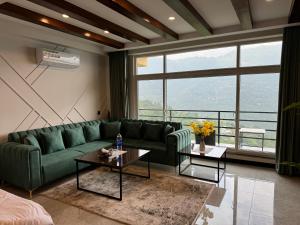 a living room with a green couch and a large window at Murree Spring Apartment in Murree