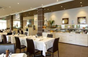 a restaurant with white tables and chairs and a kitchen at Hotel Lilia in Lido di Jesolo