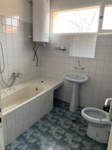 a bathroom with a tub and a toilet and a sink at Стаи за гости Villy in Kazanlŭk