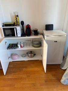 a small white kitchen with a microwave and a refrigerator at BLUE HOUSE in Paliouri