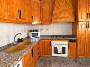 a kitchen with wooden cabinets and a sink and a microwave at Villa 365 in La Rábita