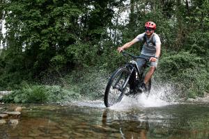 ein Mann, der mit dem Fahrrad durch einen Fluss fährt in der Unterkunft Sonic Alchemy Studio BnB in Castel Focognano