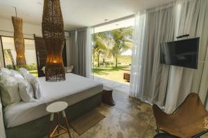 a bedroom with a bed and a tv and a balcony at Pe na Areia Boutique Hotel in Japaratinga