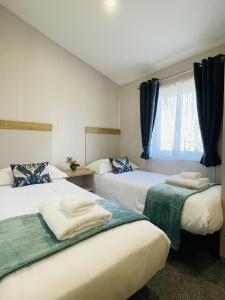 a bedroom with two beds and a window with blue curtains at Fleece Lodge in Bledington
