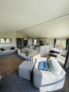 a living room with white couches and a kitchen at Fleece Lodge in Bledington
