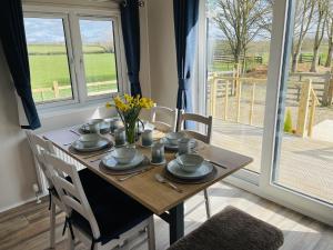 a dining room table with chairs and a table with flowers at Fleece Lodge in Bledington