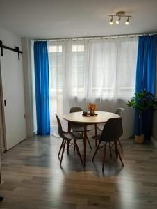 a table and chairs in a room with blue curtains at Apartament Superjednoska Spodek Centrum Nowoczesny Apartament Wifi in Katowice +5 photos