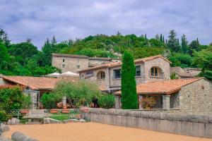 a large stone house in the middle of a yard at Hôtel La Garenne in Labeaume